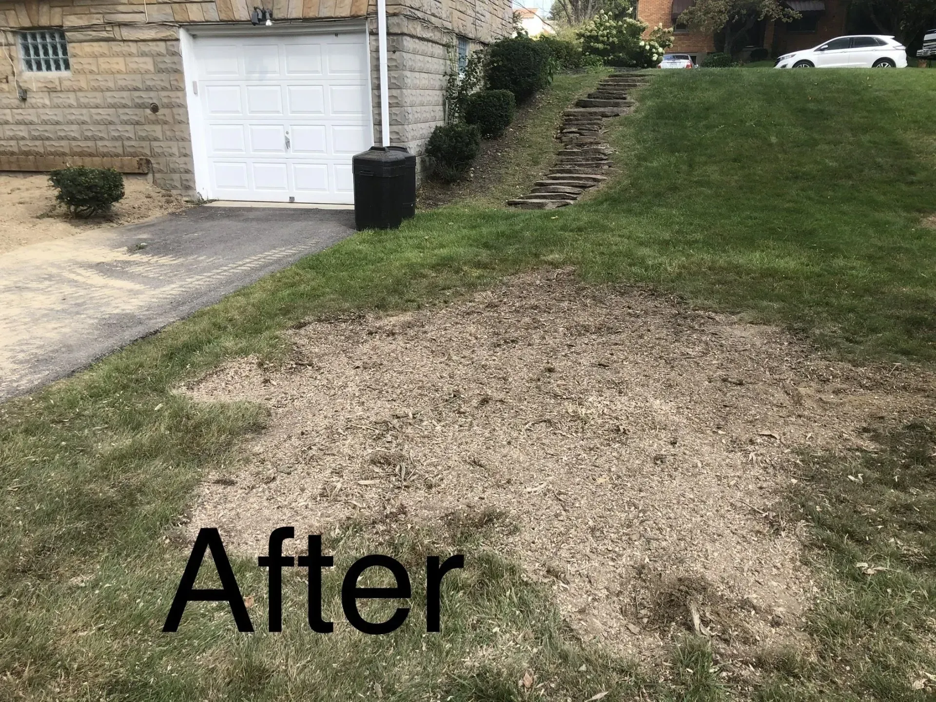 An area of dirt in a grassy yard after an event, next to a garage. 
