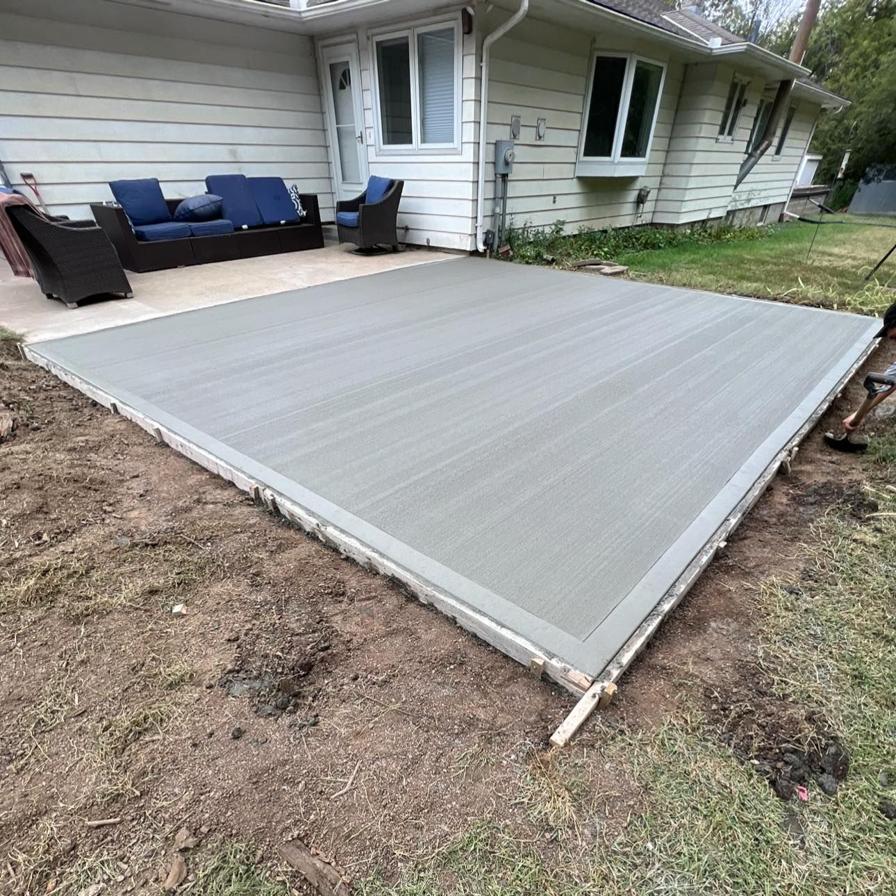A concrete patio is being built in front of a house.