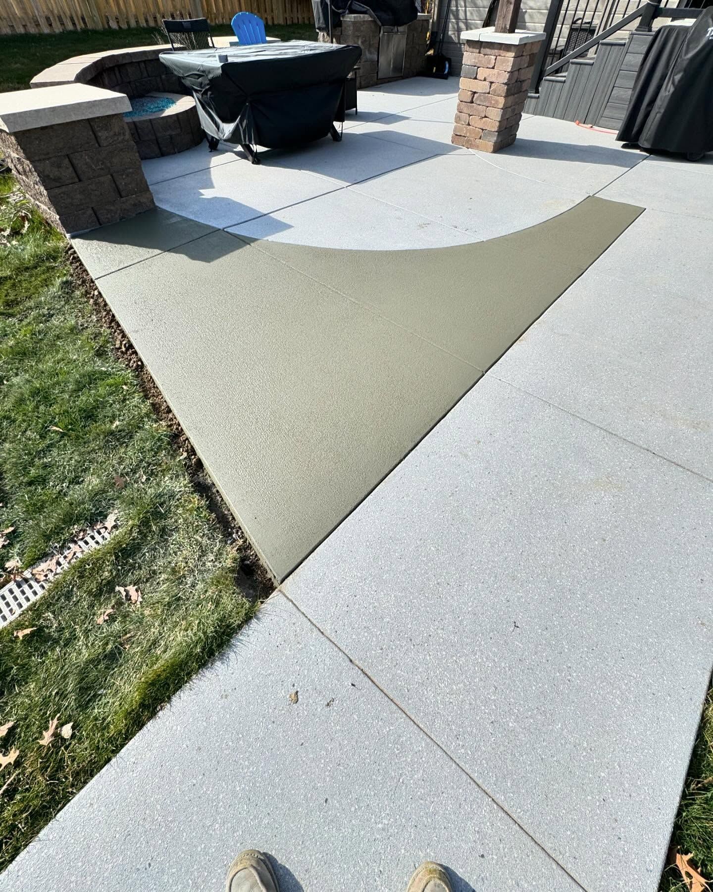 A person is standing on a sidewalk next to a patio.