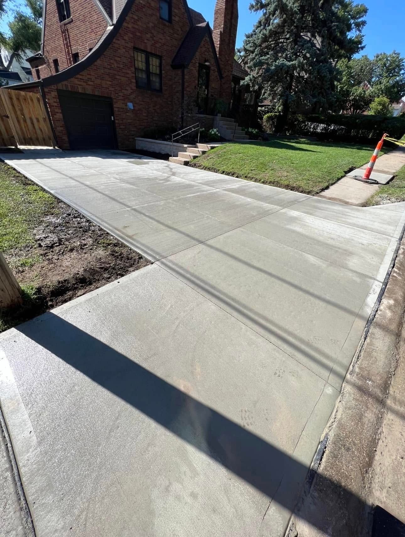 A brick house with a concrete driveway in front of it.
