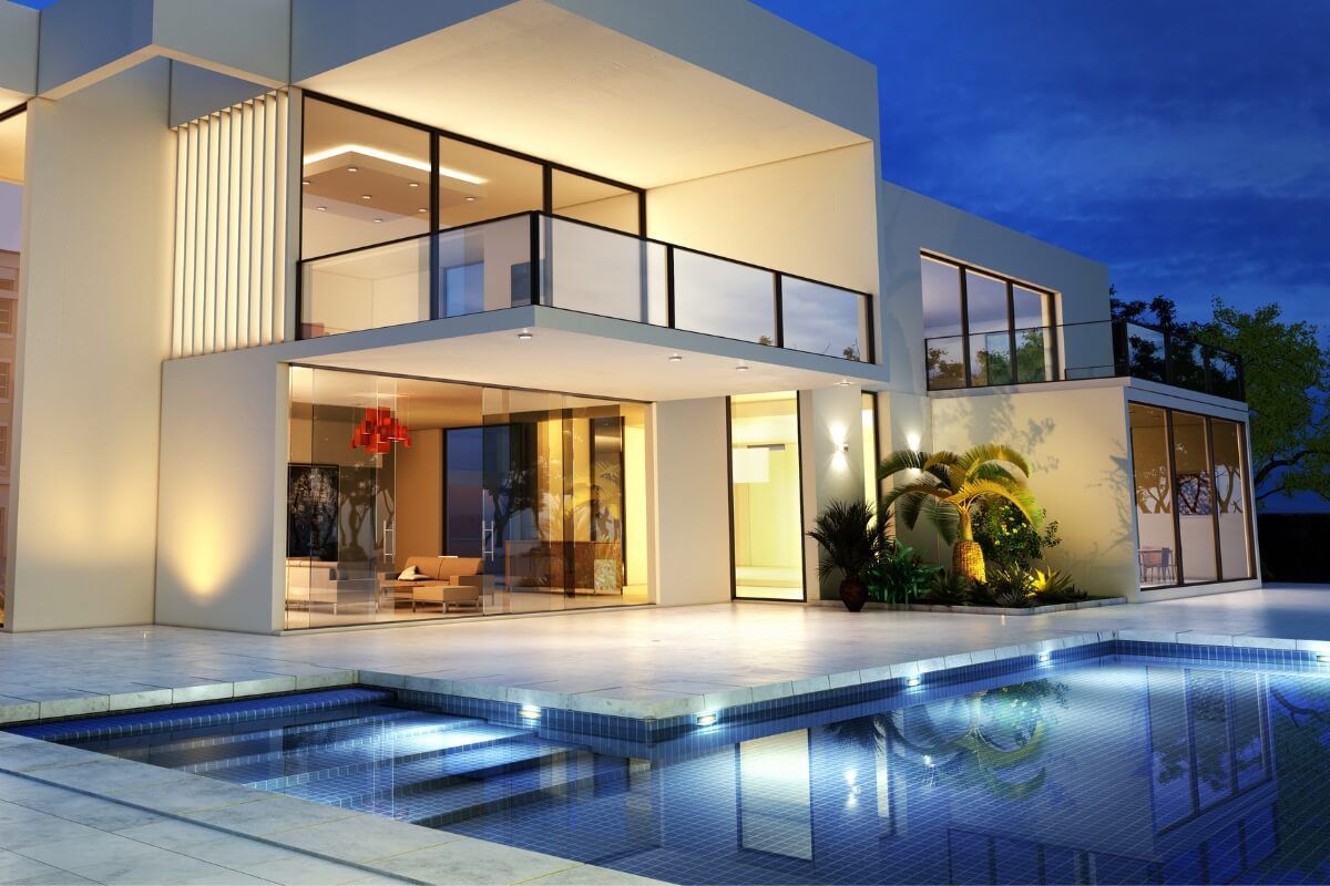 Modern white house with a pool illuminated at night.