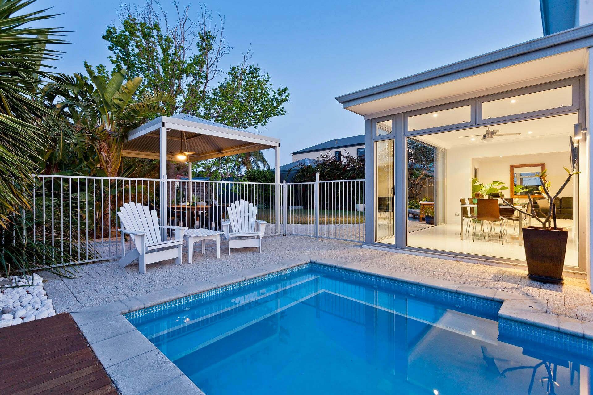Pool and patio area with chairs, gazebo, and house visible. Blue pool, white patio.