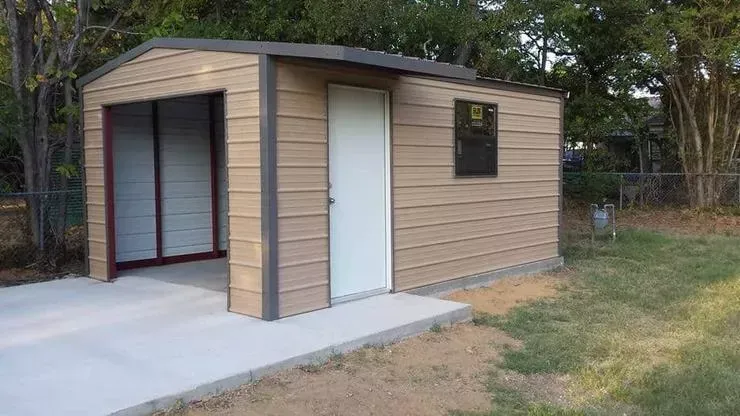 Small tan modular building with a concrete ramp and entry, set beside a grassy yard.