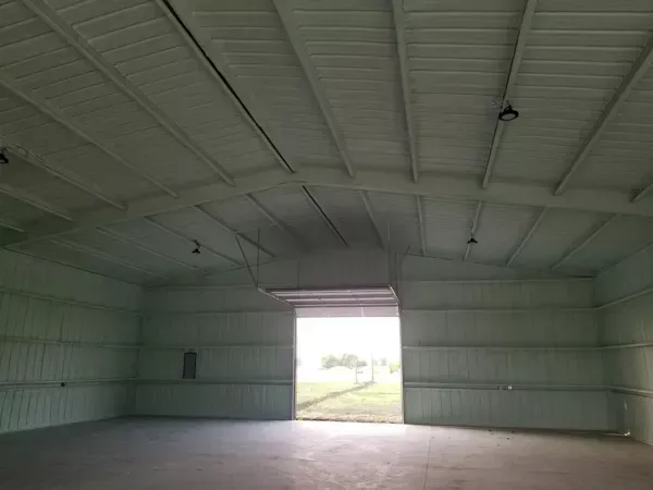 Empty metal warehouse interior with open doorway and bright daylight outside
