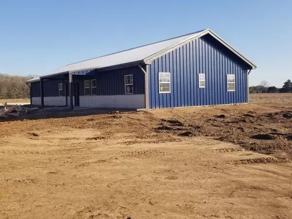 Blue metal building on a dirt lot under a clear sky