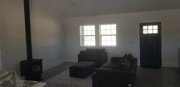 Living room with wood stove, sofa, windows, and a blue door