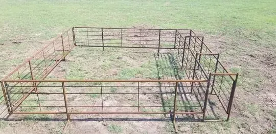 Rusty metal animal pen in a grassy field, viewed from above