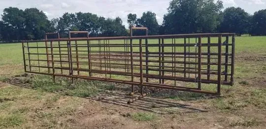 Metal livestock pen in a grassy field with trees in the background