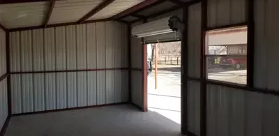 Empty metal-walled room with a doorway and window opening to the outside street.