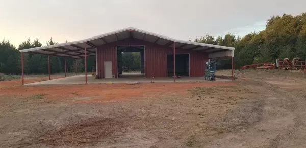 Red-roofed rural building on a bare dirt lot at dusk