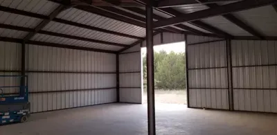 Empty metal warehouse interior with open bay doors and concrete floor