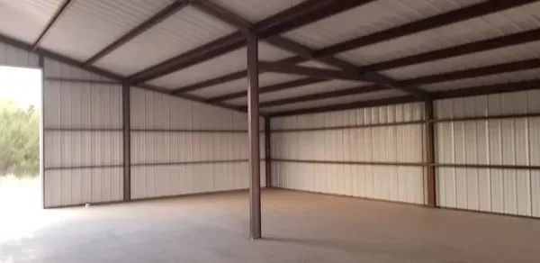 Empty metal-framed warehouse interior with corrugated walls and open doorway