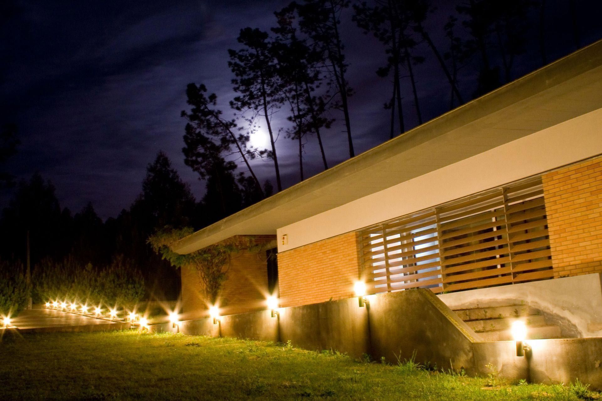 A house is lit up at night with trees in the background