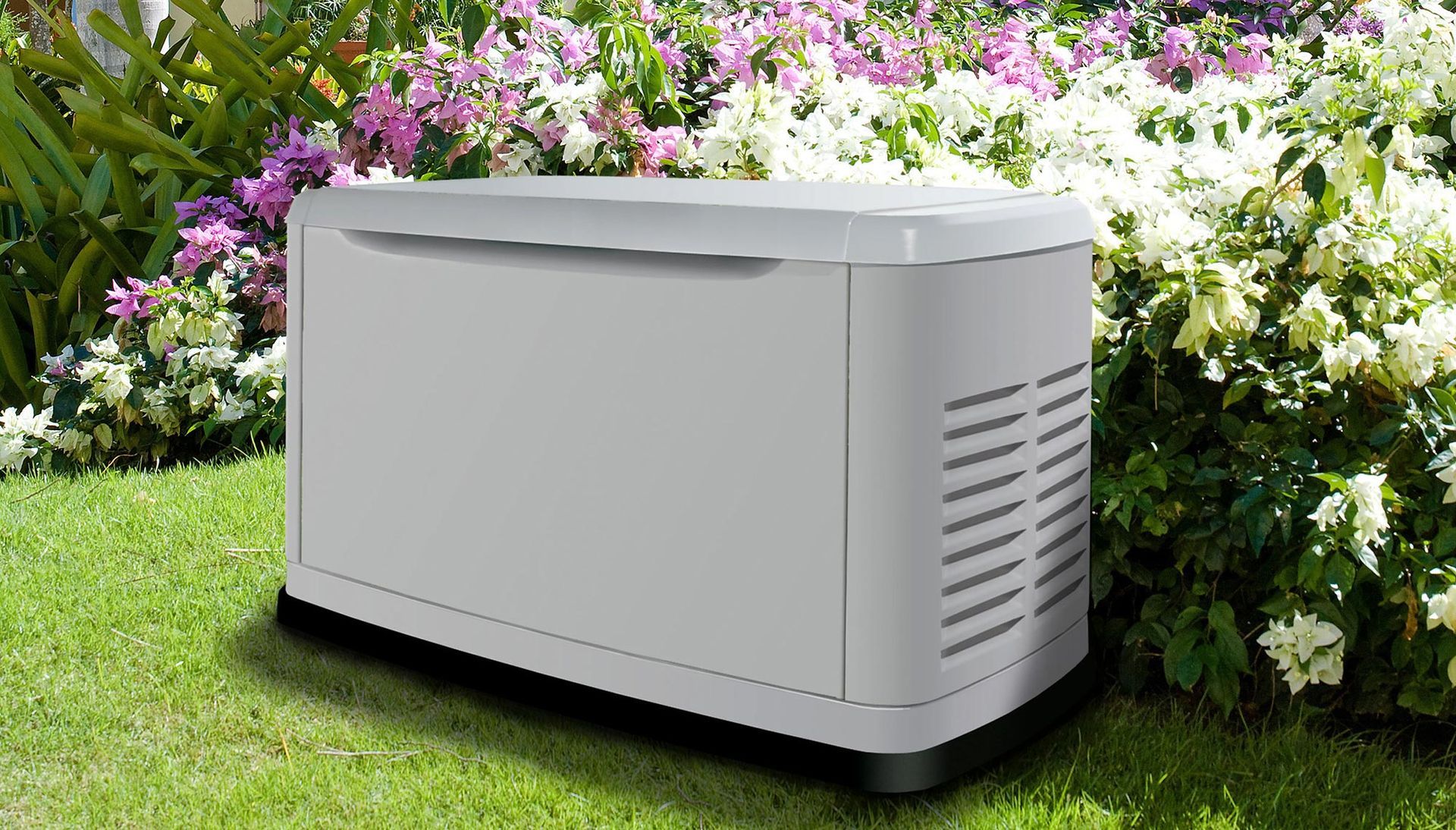 A white box is sitting in the grass next to flowers.