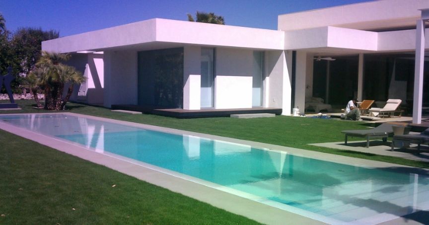 A white house with a large swimming pool in front of it