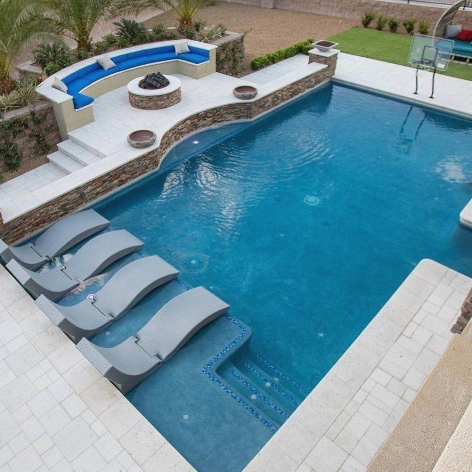 A large swimming pool with a fire pit and lounge chairs