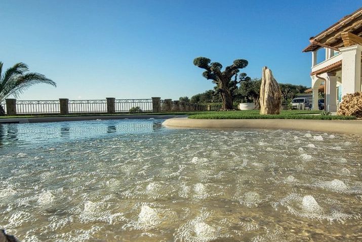A large swimming pool with a house in the background