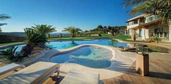 A large swimming pool with a house in the background