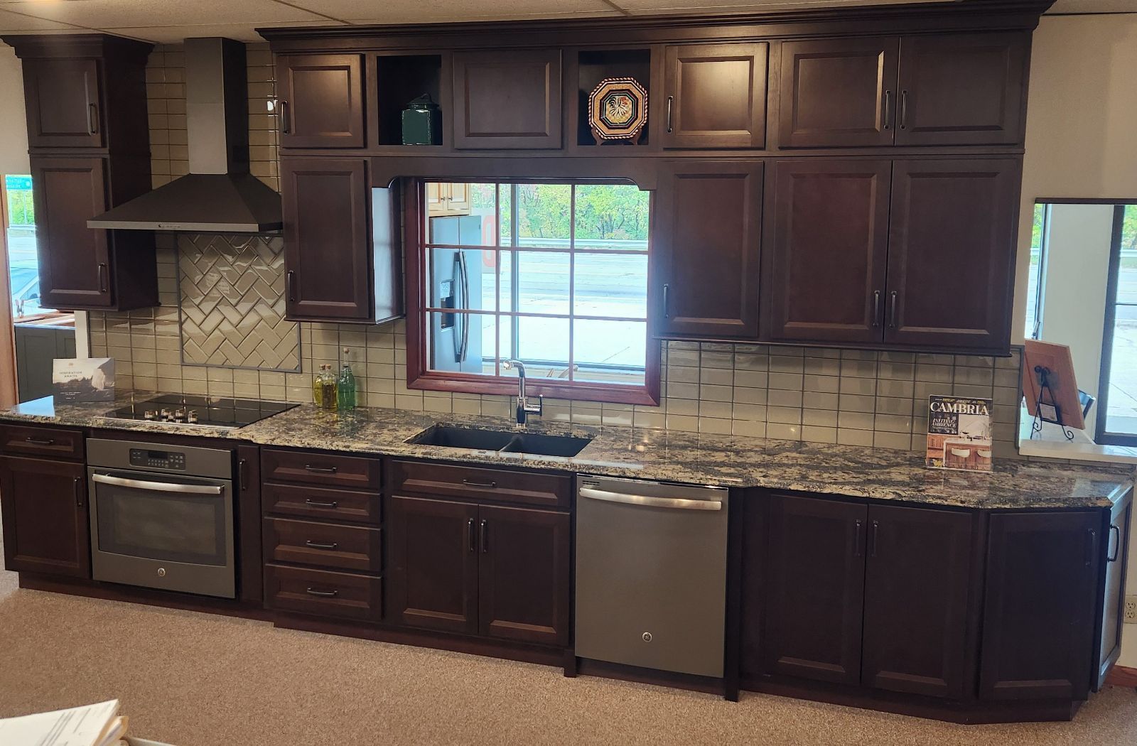 A kitchen with wooden cabinets, granite counter tops, stainless steel appliances, and a large window.