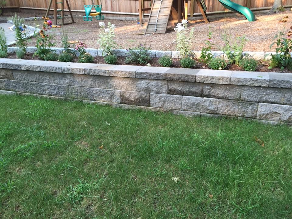 A backyard with a brick wall and a playground in the background.