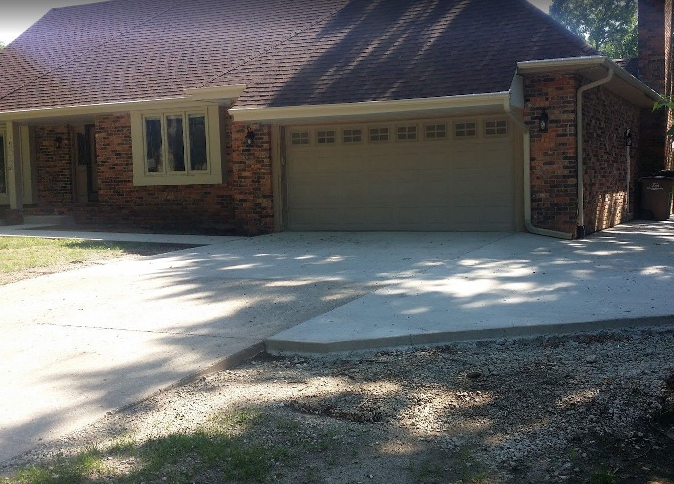 Brick house with tan garage door and driveway.