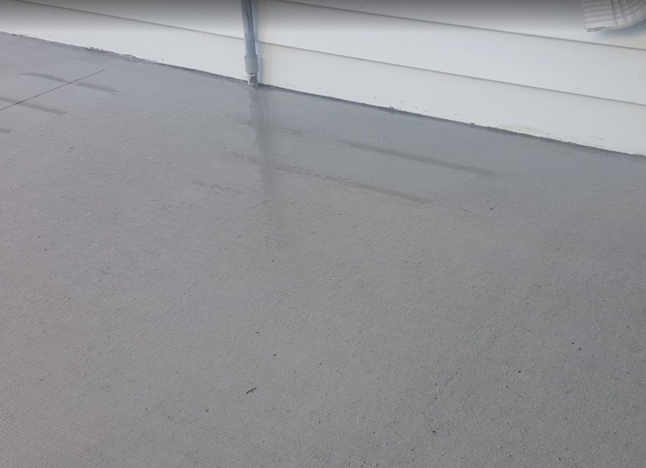Gray concrete surface next to a white wall.