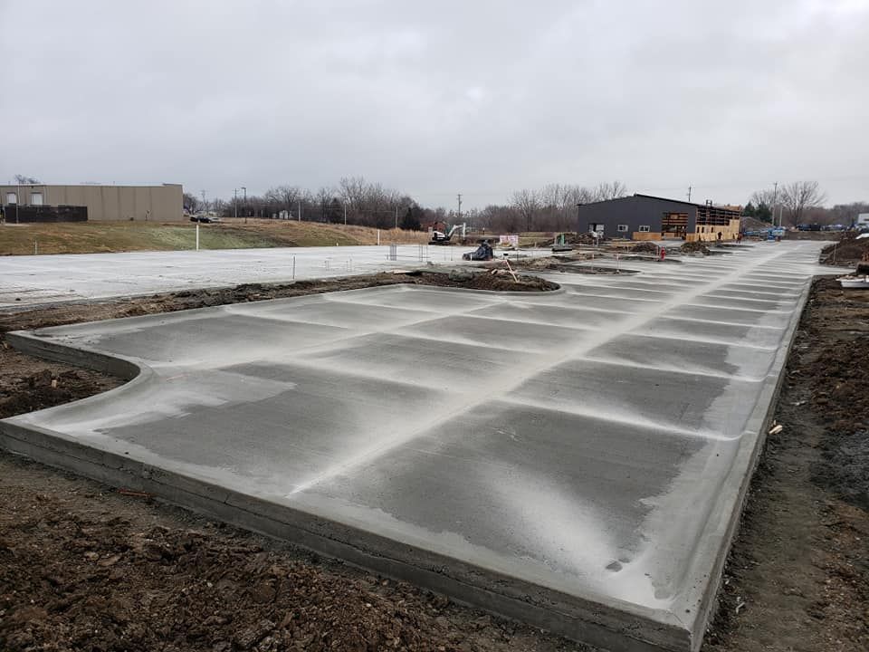 Newly poured concrete slab, divided into rectangular sections, under an overcast sky.