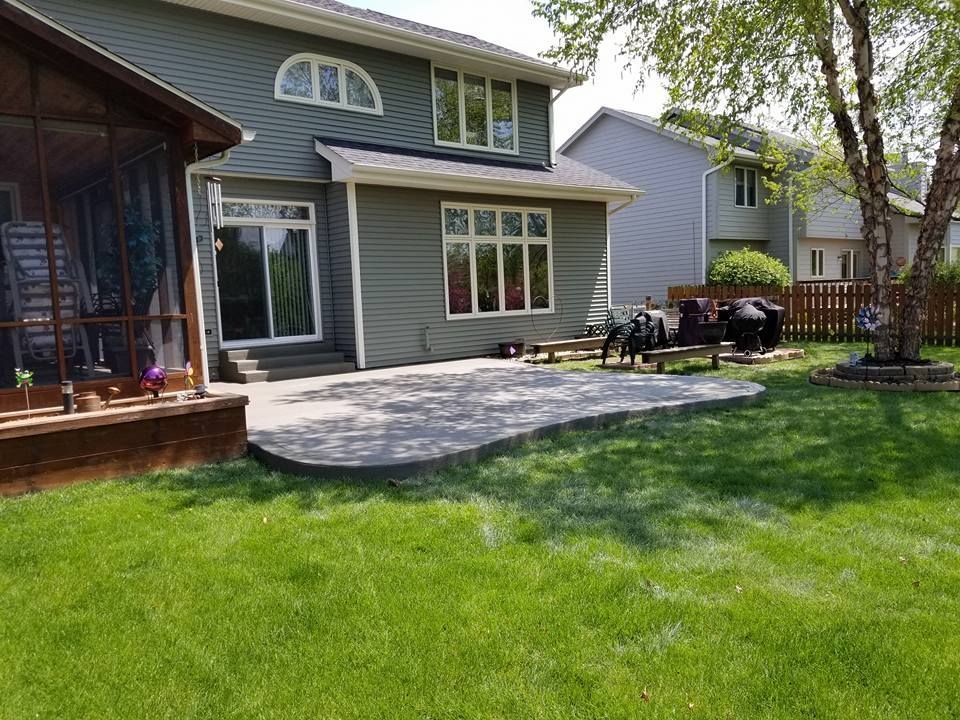 Backyard with patio, green siding house, lawn, and screened porch.
