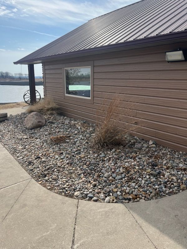 A brown house with a metal roof is sitting next to a lake.