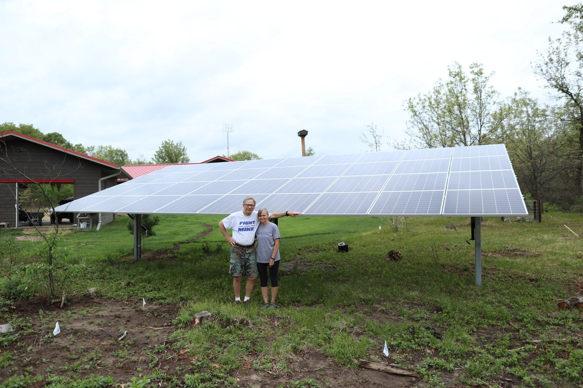 A man and a woman are standing in front of a large solar panel.