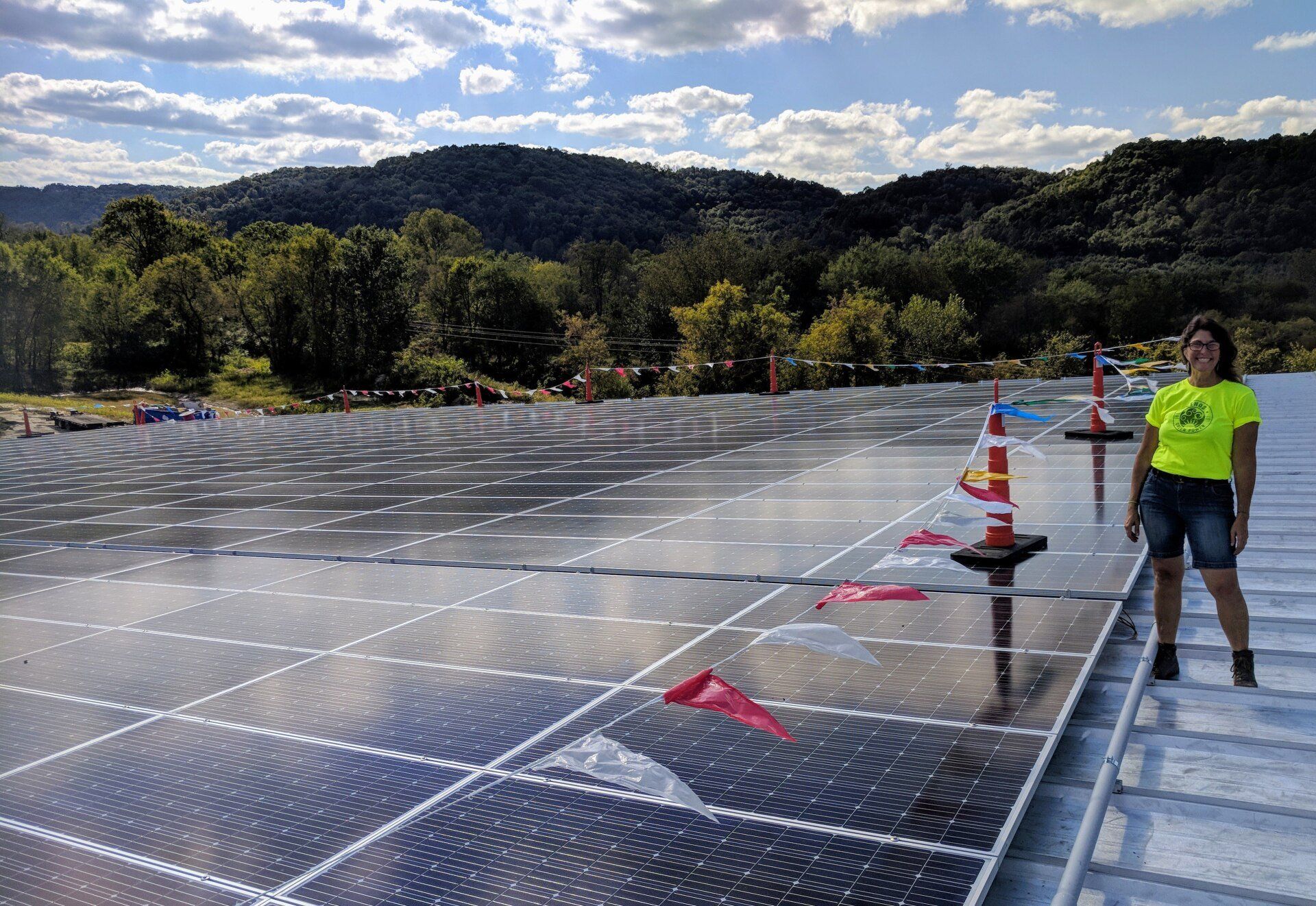A woman is standing on top of a roof with solar panels.