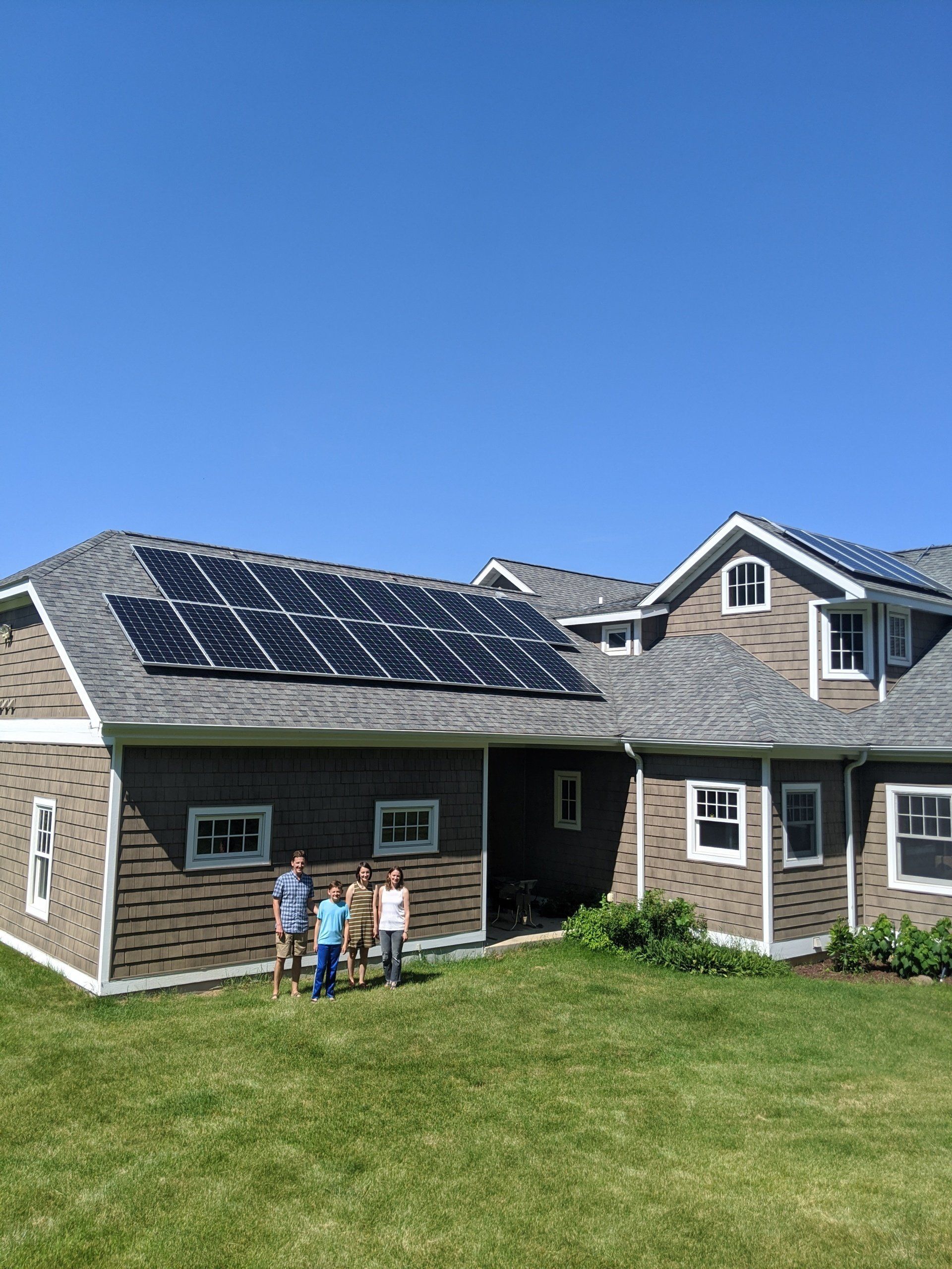 Two people standing in front of a house with solar panels on the roof