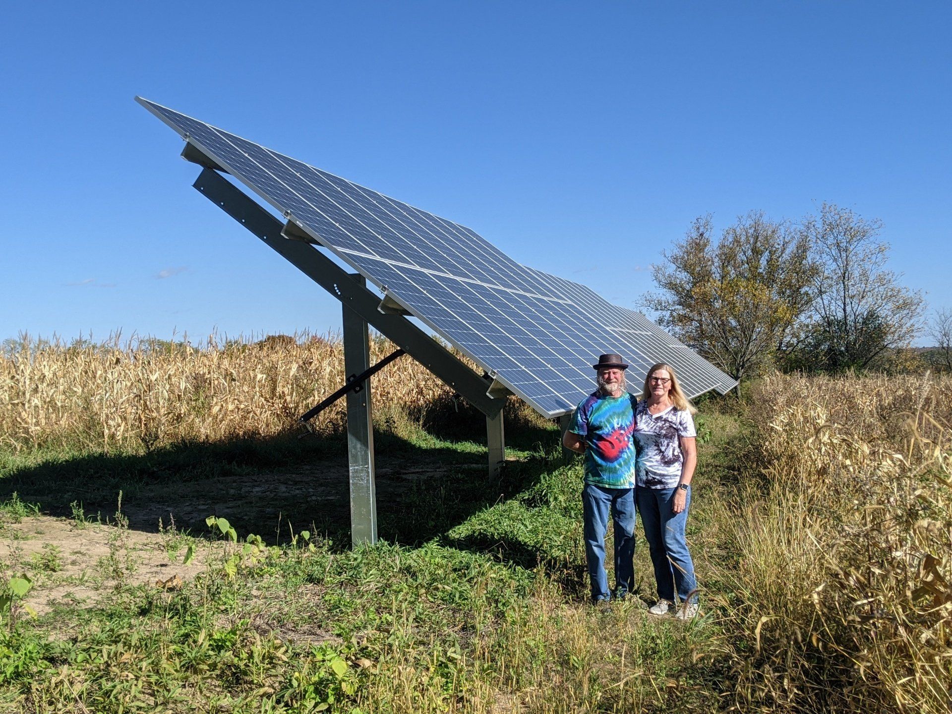 A man and a woman are standing in front of a large solar panel.