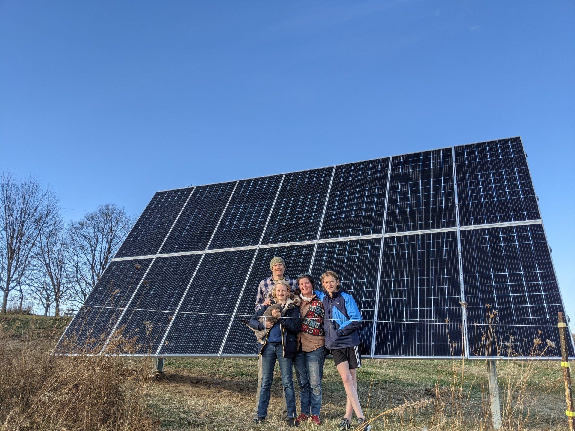 A group of people are standing in front of a large solar panel.