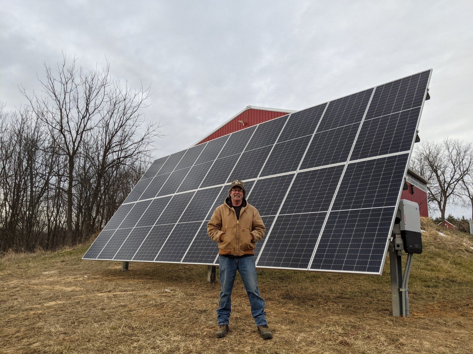 A man is standing in front of a large solar panel.