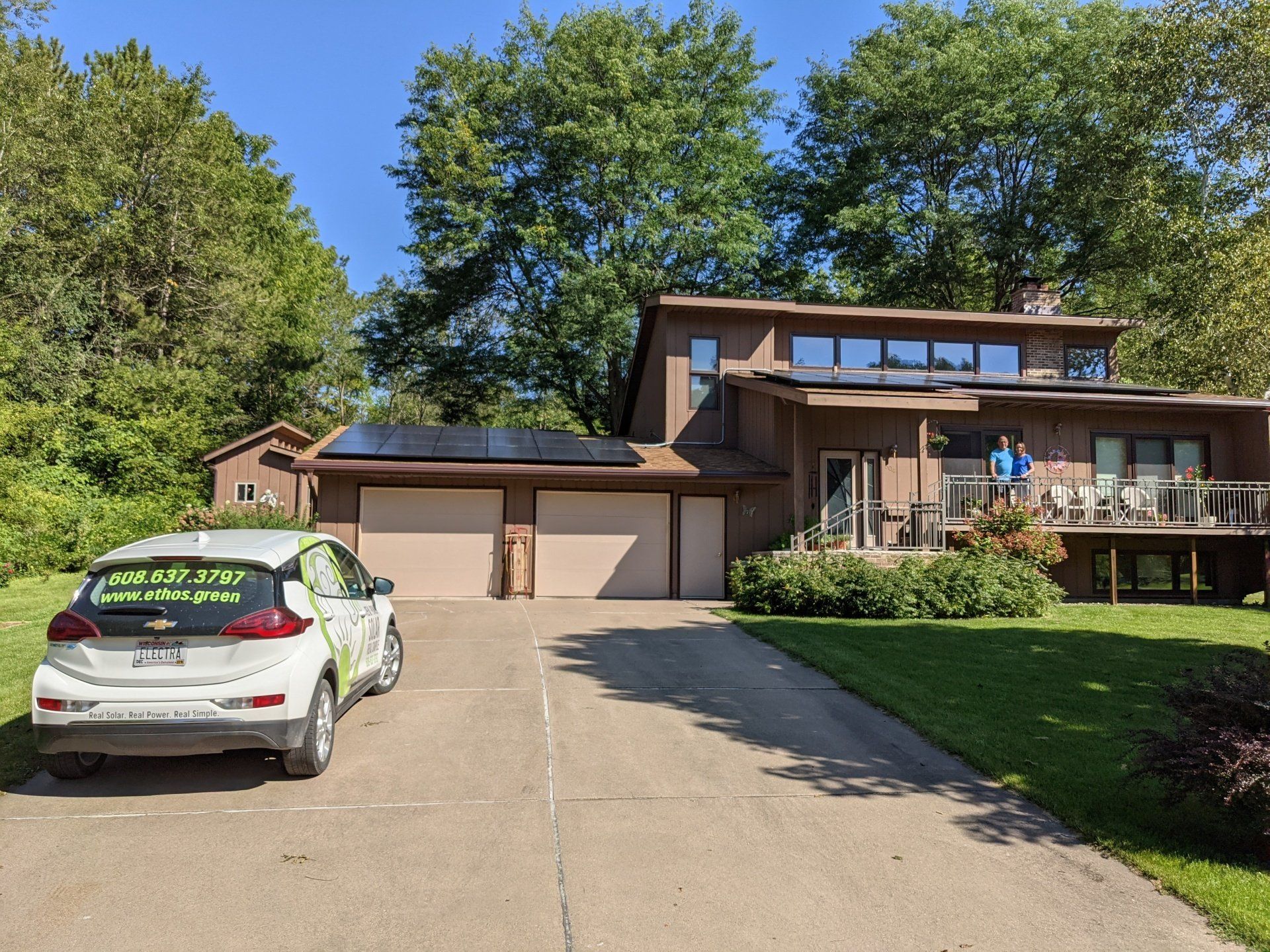A car is parked in front of a house with solar panels on the roof