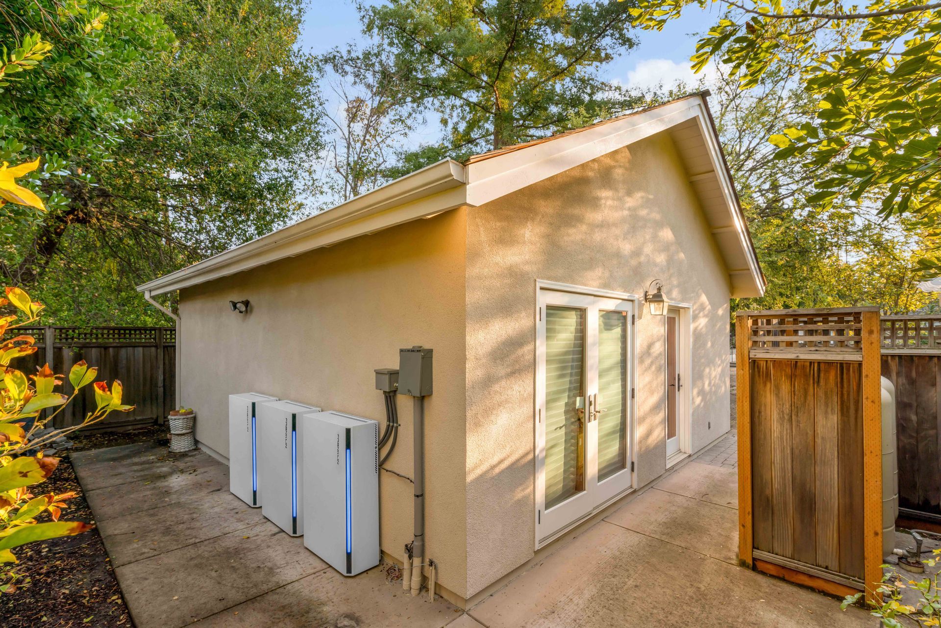 A small house with a fence and a shed in the backyard