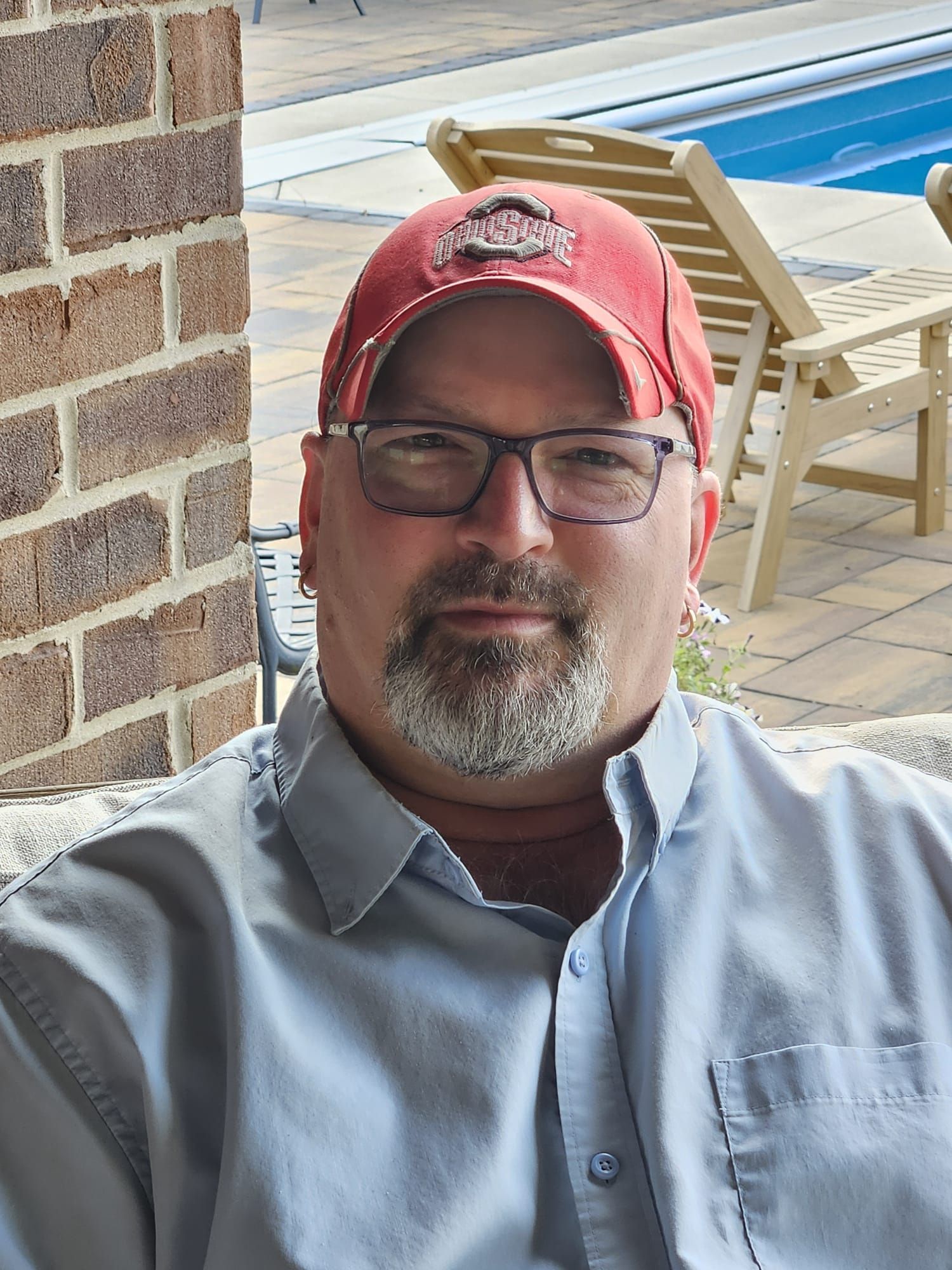 A man with glasses and a beard is wearing a maroon sweater.