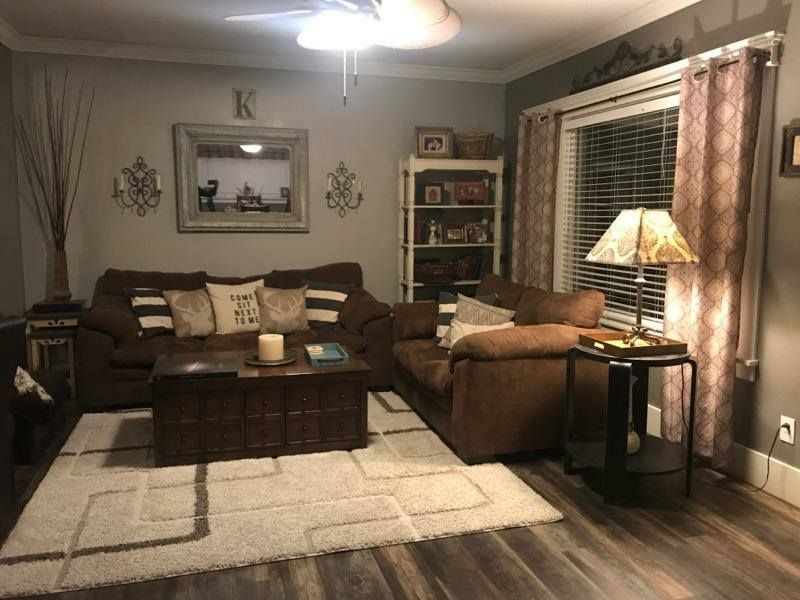 Cozy living room with brown sofa, rug, coffee table, and patterned curtains.