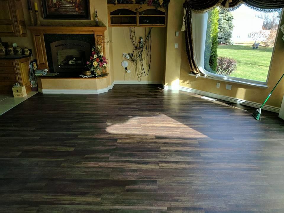 Dark wood floor in a brightly lit room with a fireplace, large window, and decorative wall accents.