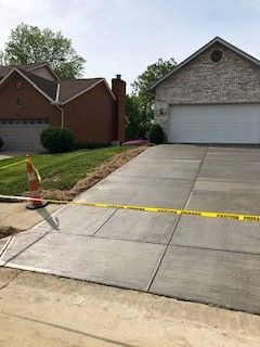 Newly poured concrete driveway with caution tape in front of a house.