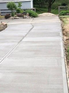 Concrete driveway with a crack running through it, leading towards a house.