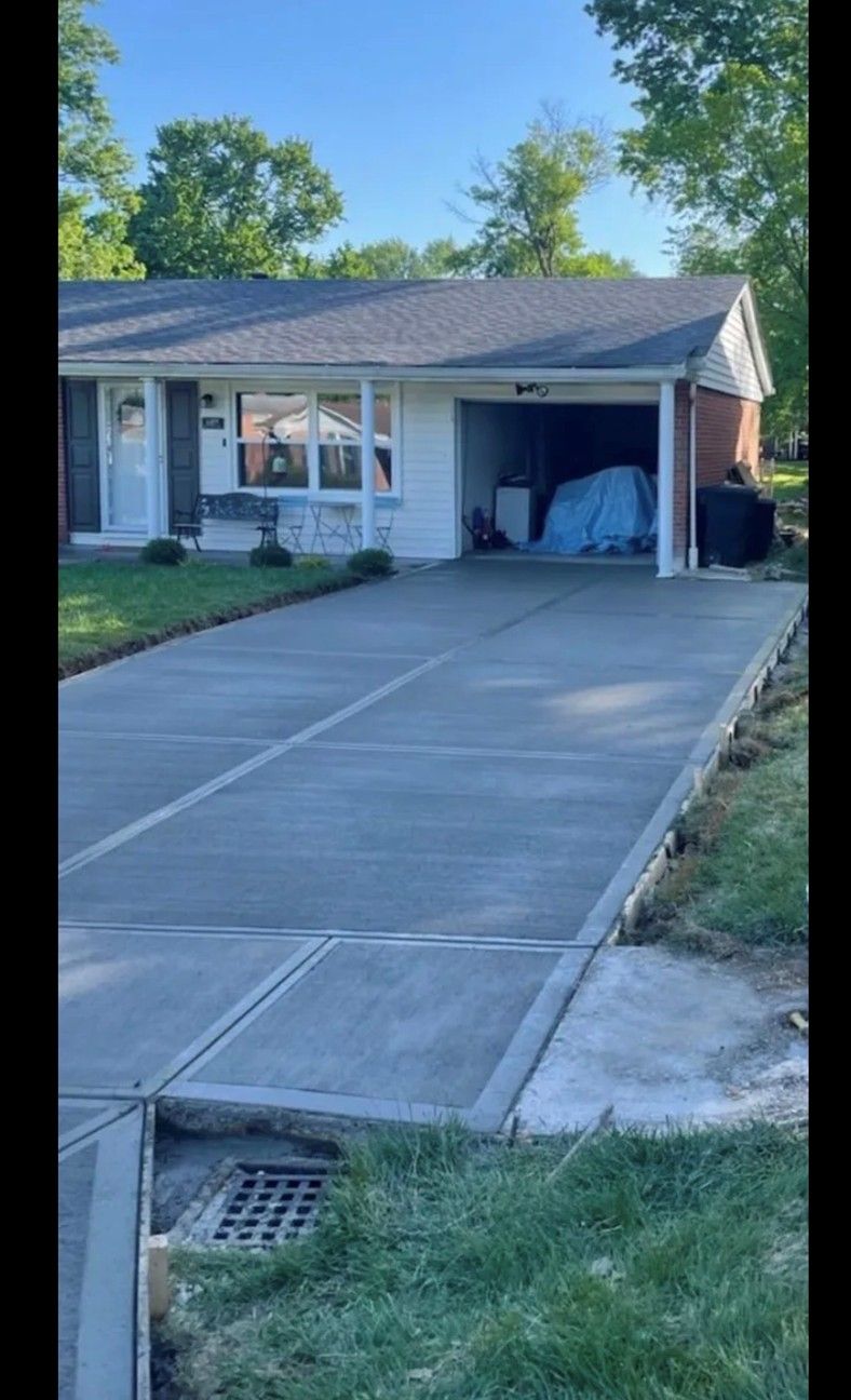 Freshly poured concrete driveway in front of a white house with a garage, under a blue sky.