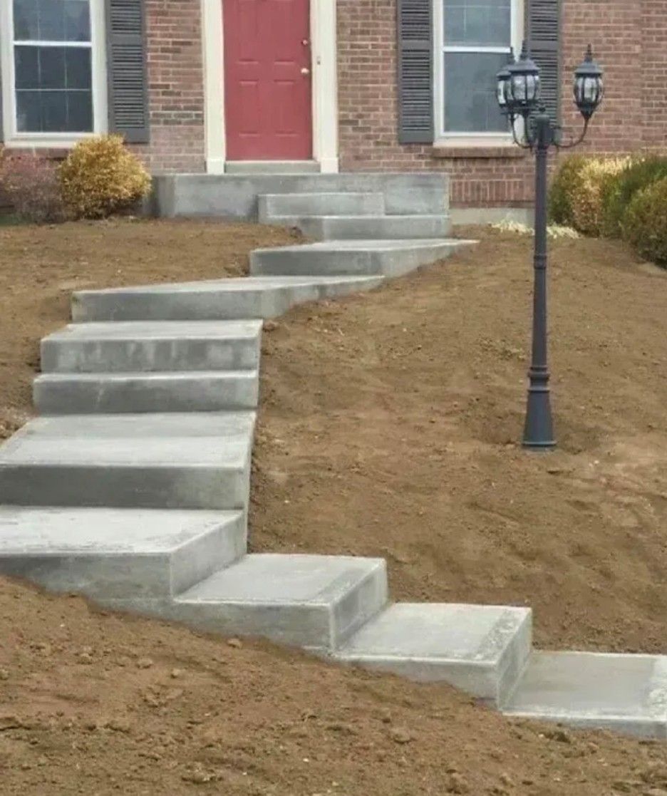 Concrete steps leading up to a house with a red door. A lamppost stands beside the steps in the yard.