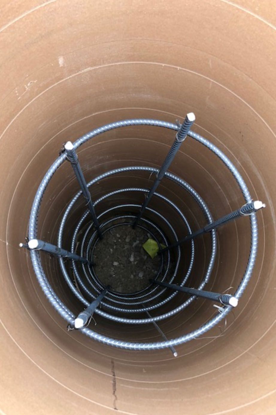View from above into a cylindrical hole, showing a rebar cage inside.