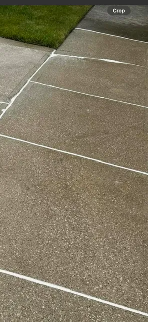 Concrete walkway with white lines dividing the sections; green grass in the top left corner.