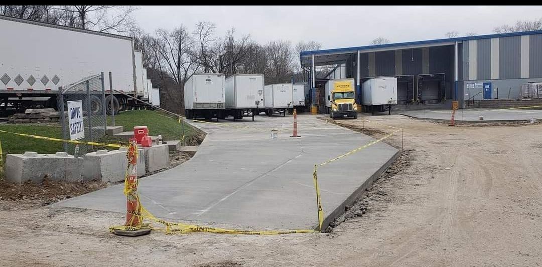 A truck scales area with parked semis and a truck entering a loading dock.