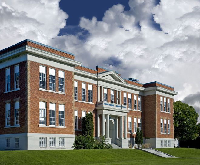Brick school building with white trim under a cloudy sky.