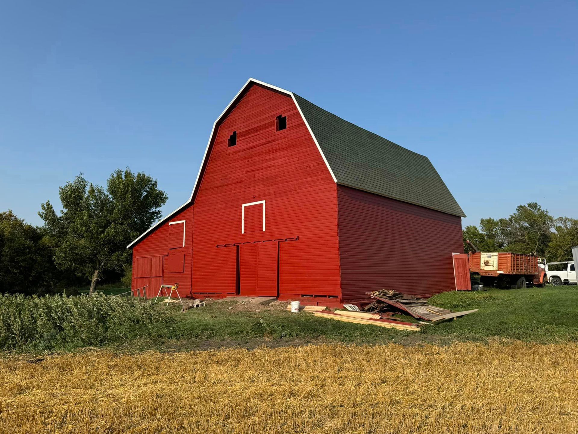 A large red barn is sitting in the middle of a field.