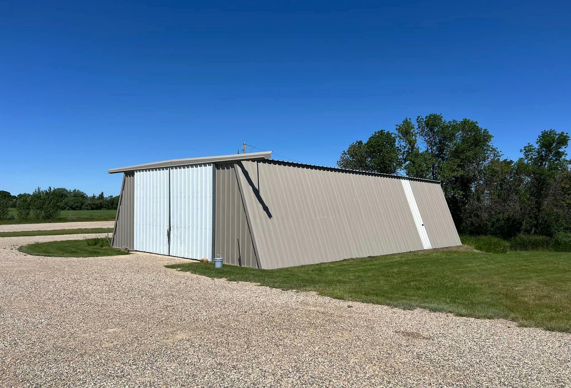 A shed is sitting in the middle of a gravel road.